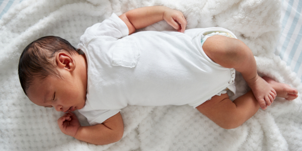 Photo of newborn baby lying on back on white blanket