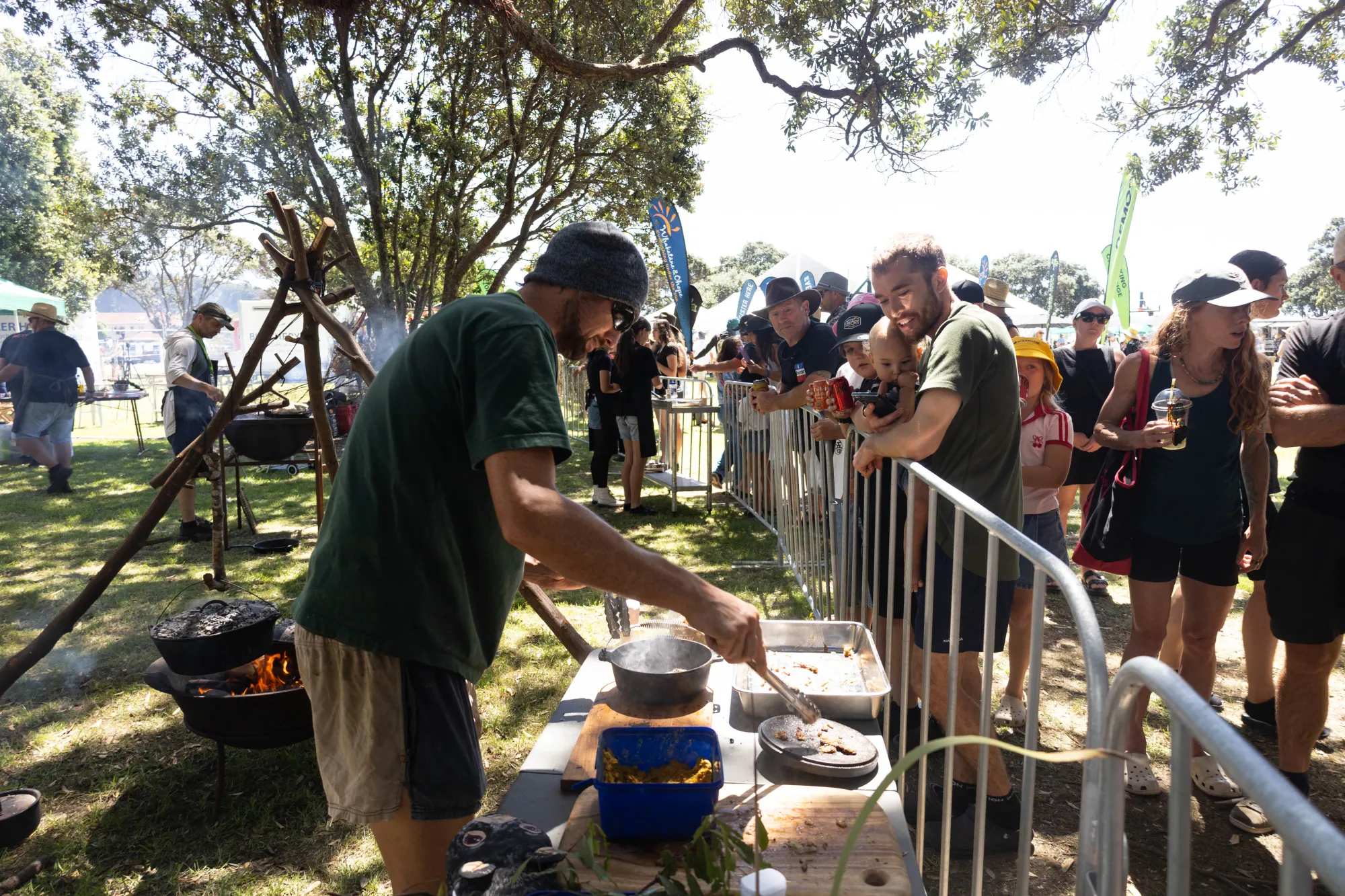 A campfire cooking demonstration drawing a crowd at the Wildfoods festival in New Zealand