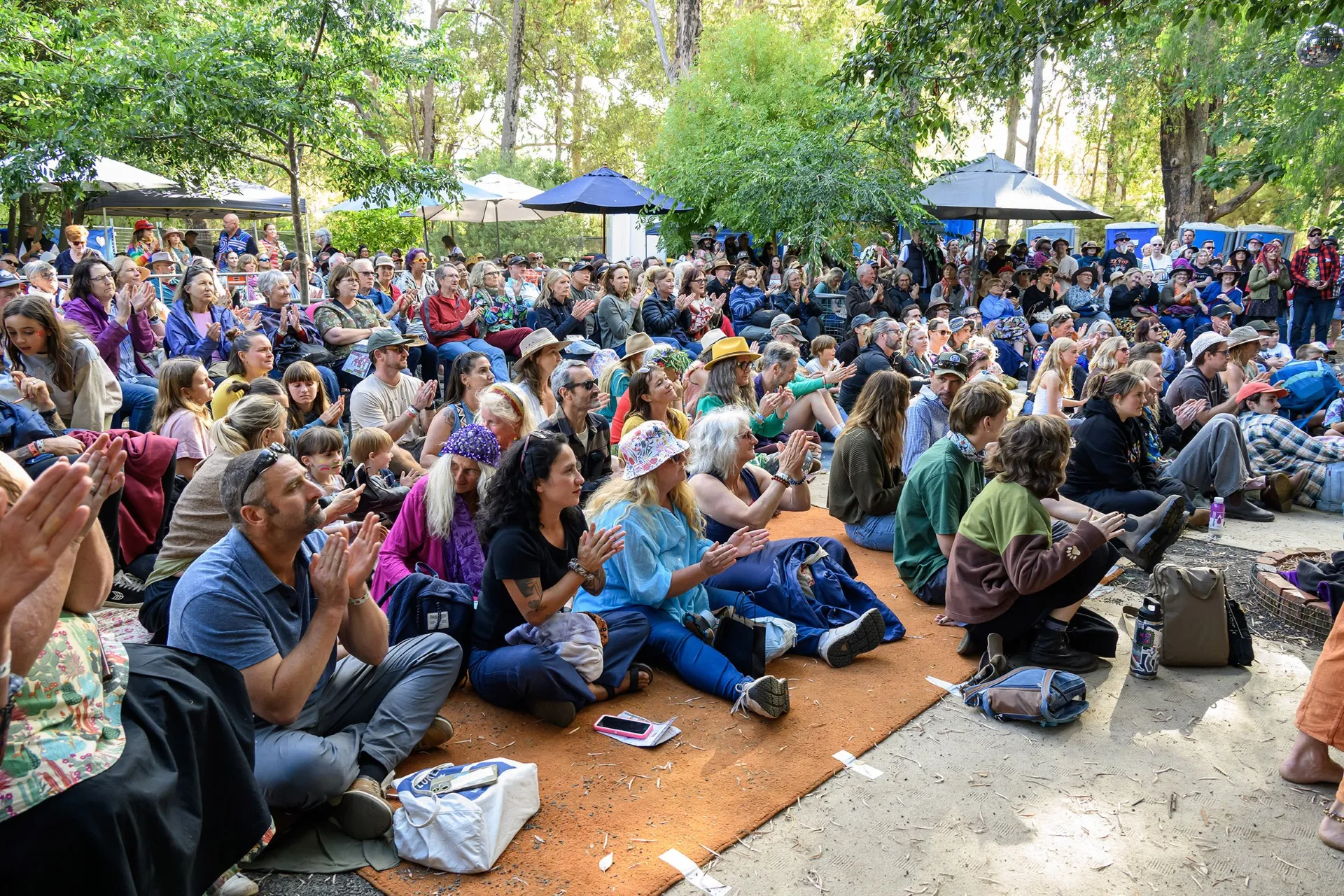 A festival crowd sitting in dappled shade at the Nannup music festival in Western Australia