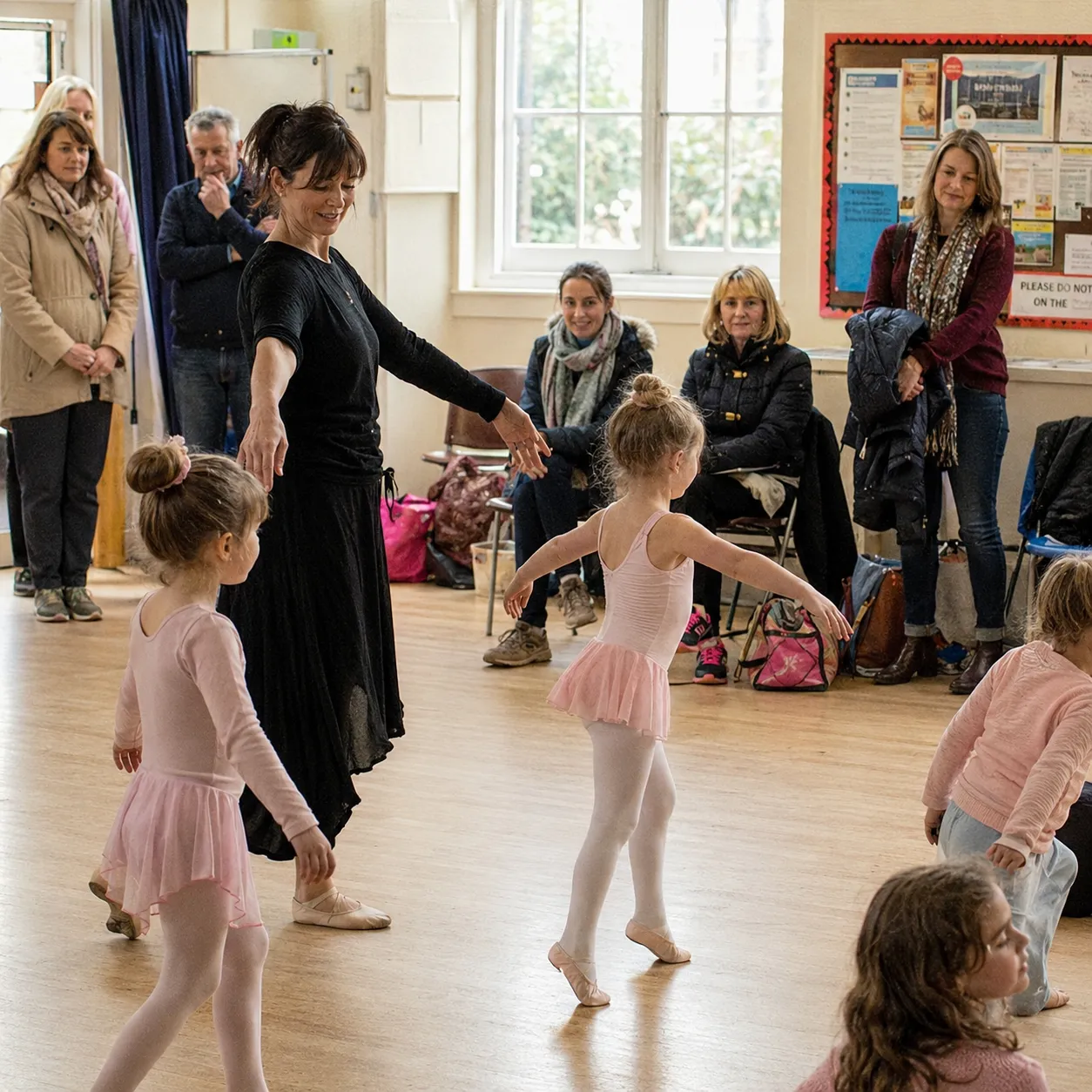 A dance teacher leading young ballet students in a studio rehearsal