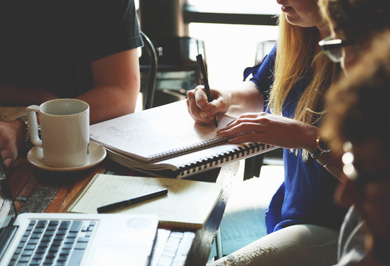 Group of workers informally sitting at a desk taking notes