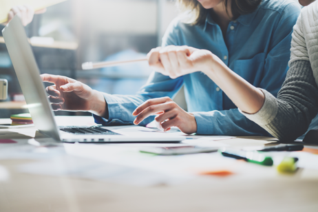 Business workers at office desk pointing to screen