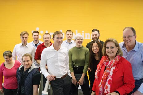 A group of team members in front of a yellow wall