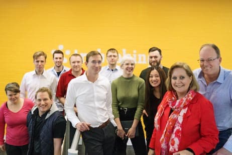 A group of team members in front of a yellow wall