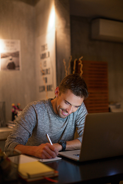 Young man looking down and smiling while working at desk