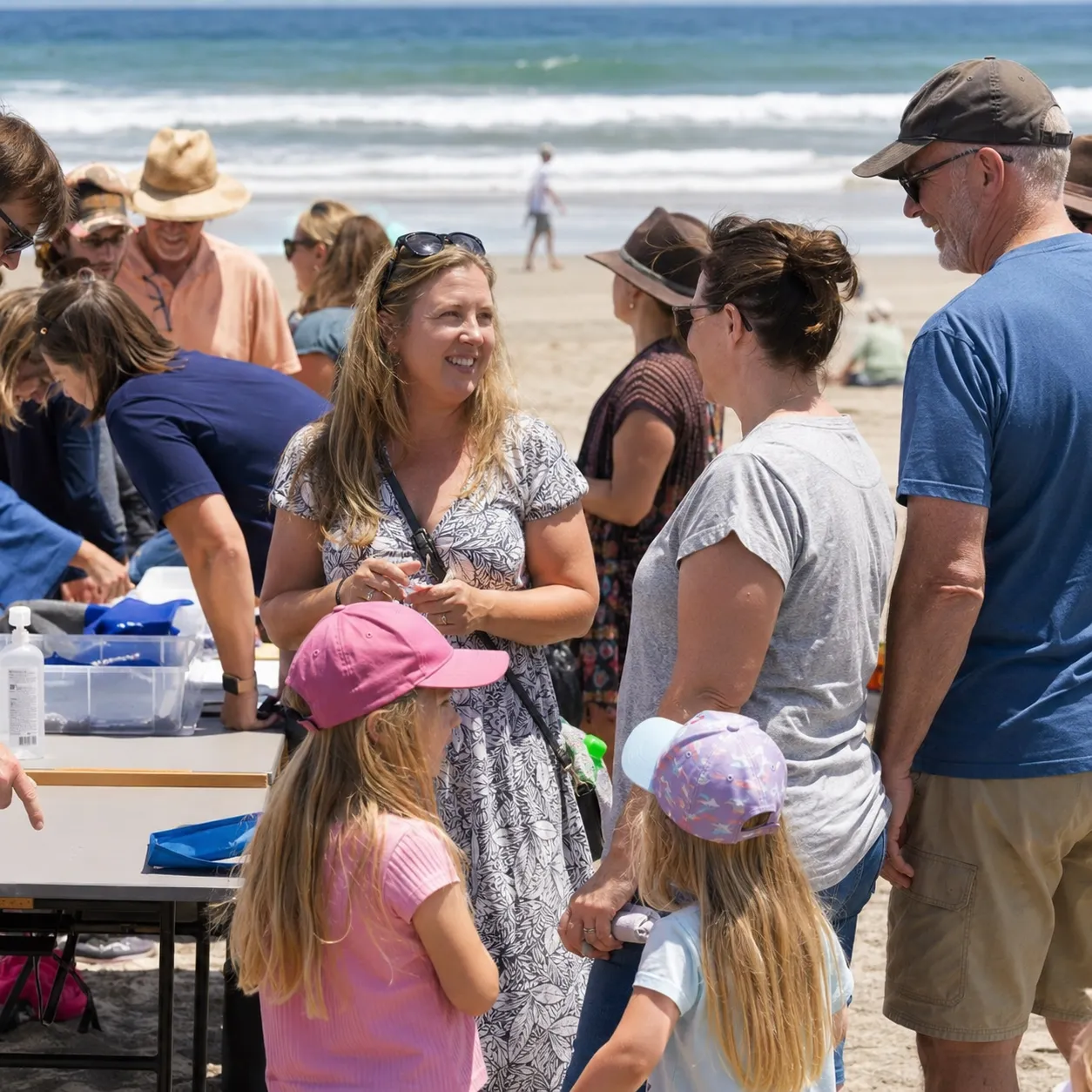 Small sailing boats and spectators gathered at a beachside regatta event