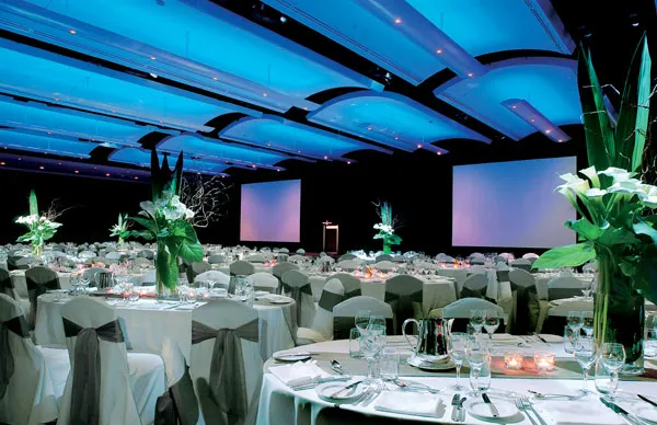 Round tables set with formal place settings in a ballroom before a school formal