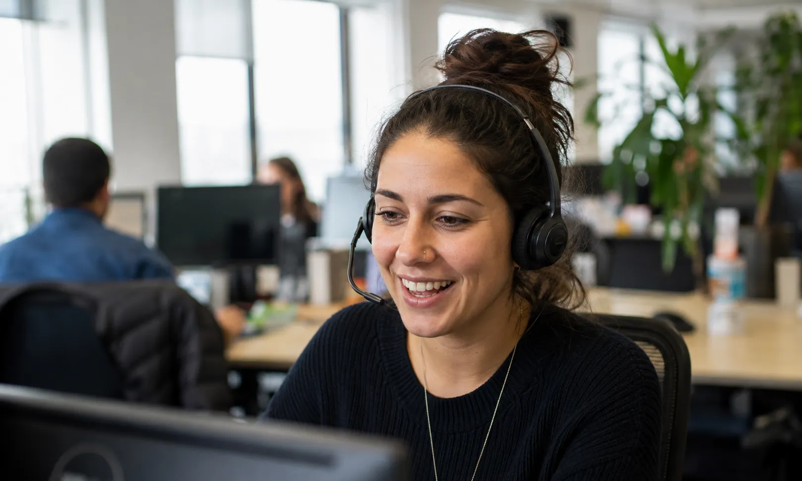 A support team member wearing a headset at her desk in an open-plan office