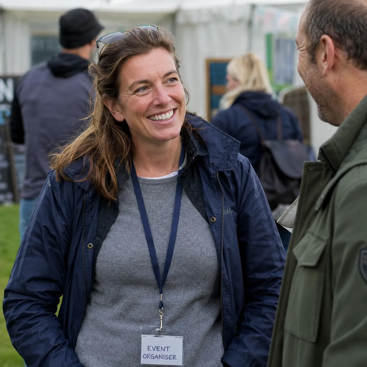 An event organiser chatting with an attendee at an outdoor event