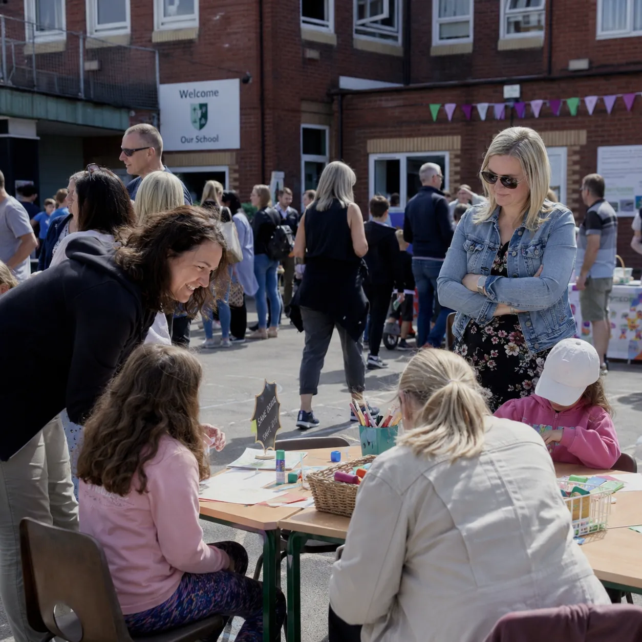 Families browsing craft stalls at a sunny school summer fair