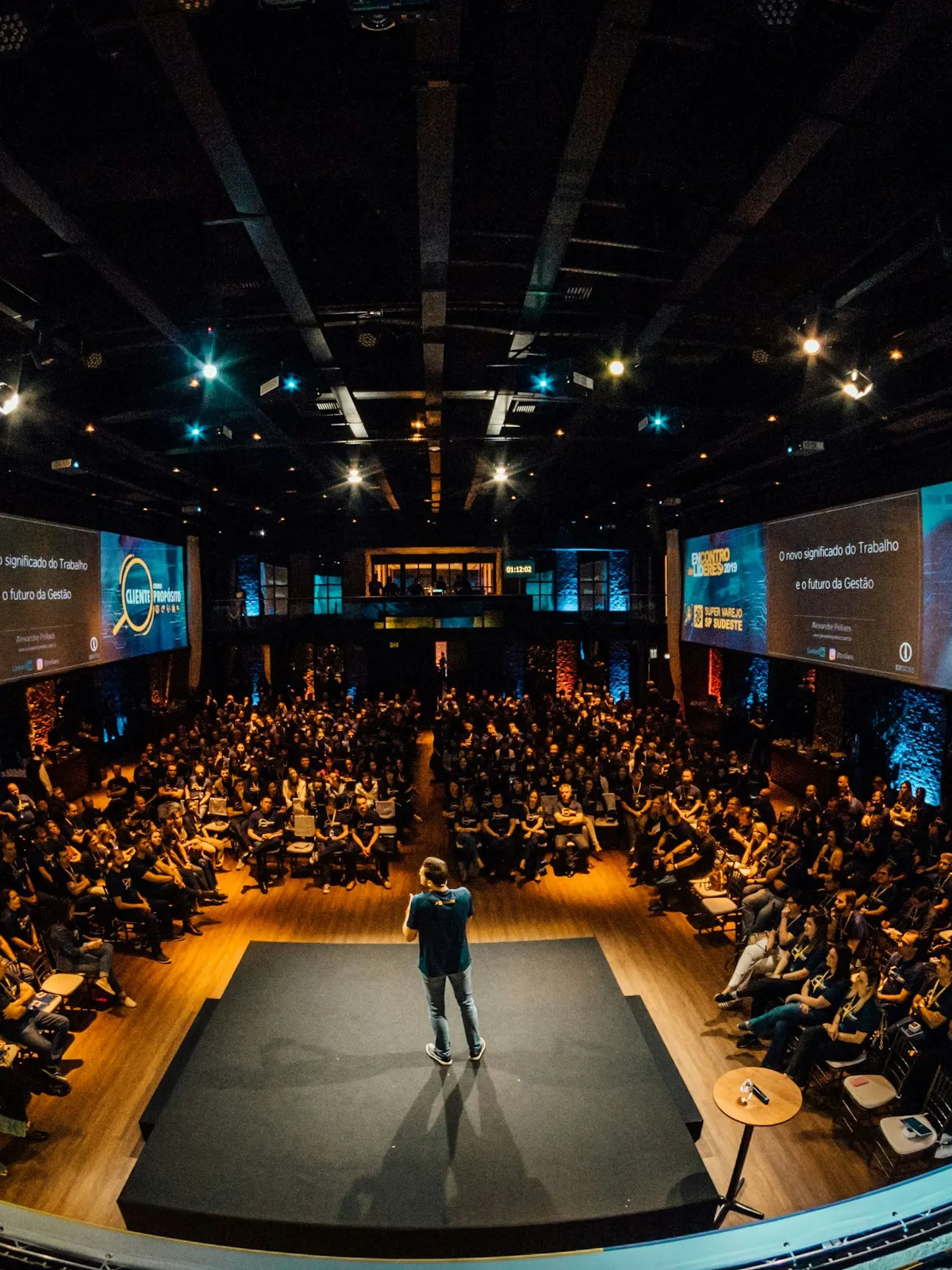 A speaker on stage addressing a full conference auditorium